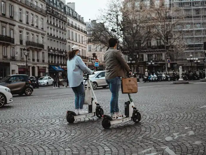 vlad-b-emjNOlbRZio-unsplash_small Mobilitätsbudget - Eine Frau auf einem Elektro-Roller und ein Mann mit einem Fahrrad.